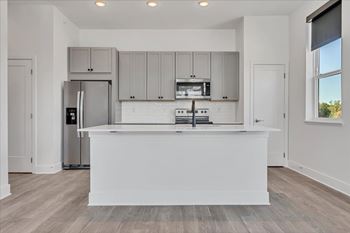 A modern kitchen with a white island and stainless steel appliances at Luxe 360 on Centerpointe Apartments, Midlothian, Virginia